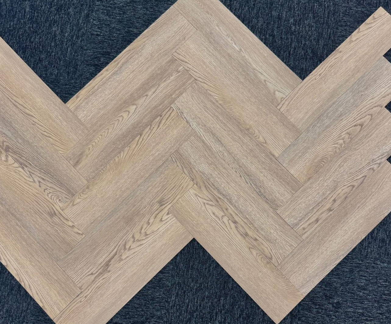 Close-up texture detail of light brown herringbone luxury vinyl tiles