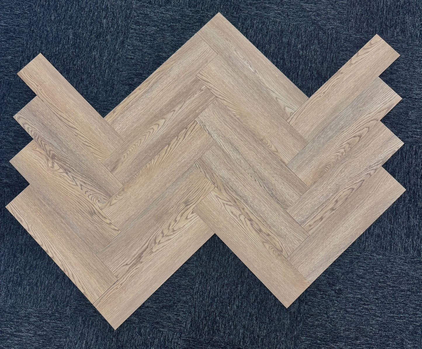 Wooden flooring tiles arranged in a herringbone pattern on a dark background