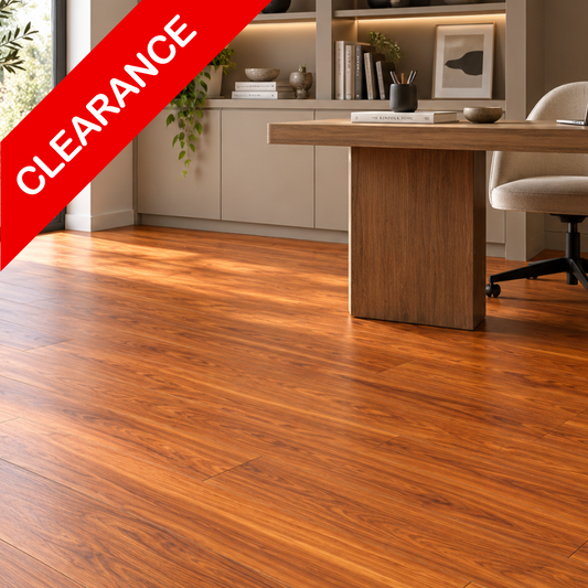 Warm medium-brown wood-look flooring planks shown in a modern home office setting with a desk, chair, and cabinets. A red diagonal banner in the top-left corner reads 'CLEARANCE'.